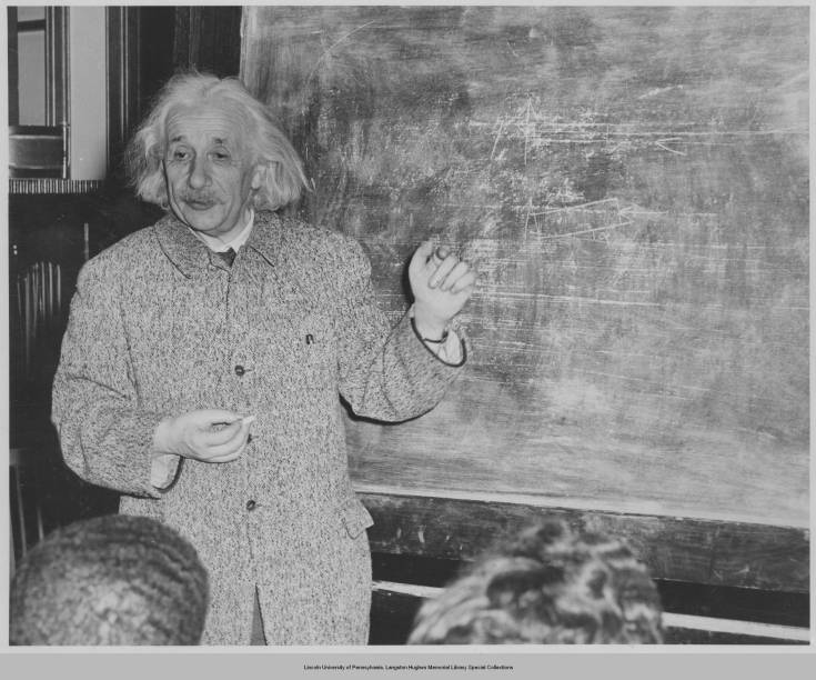 A man in a suit is standing at the blackboard